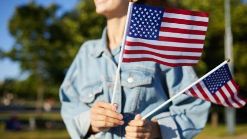 woman holding two american flags outside