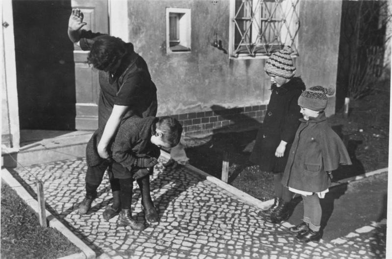 old black-and-white of adult spanking young child while two children look on